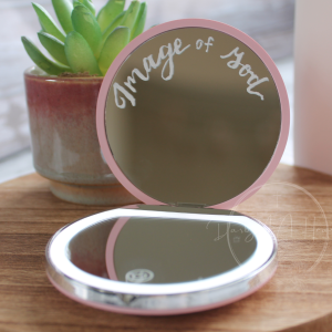 Remember your identity with this elegant light-up compact mirror, featuring the inspiring phrase “Image of God,” hand-lettered on the upper mirror.