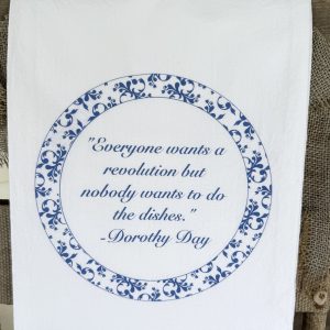 Folded white flour sack tea towel with Dorothy Day quote in blue