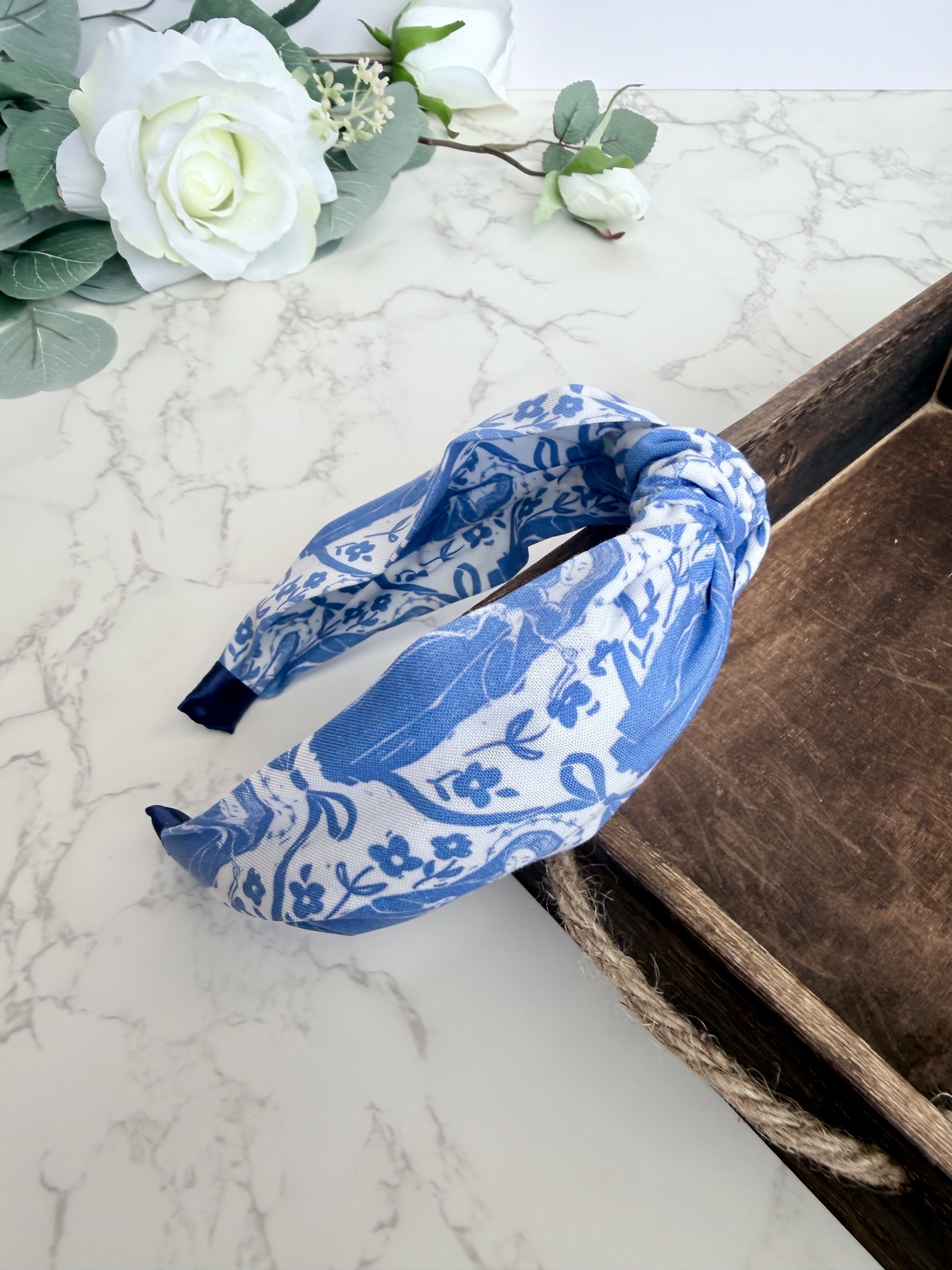 Knotted headband featuring the image of Our Lady Undoer of Knots in blue on a white background .